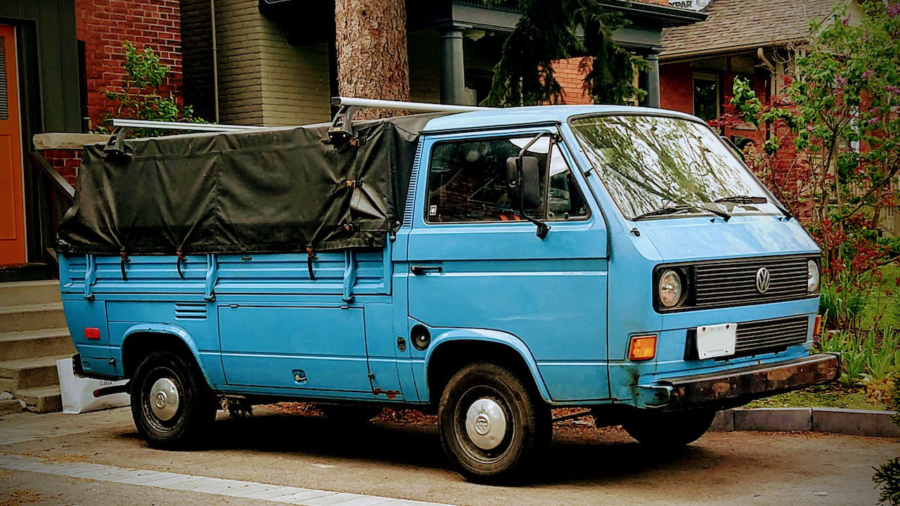 Light blue Volkswagen T3 van in a pickup style with canvas over the truck bed